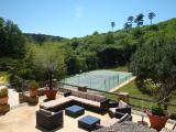 La terrasse avec salon de jardin et le tennis en contre-bas